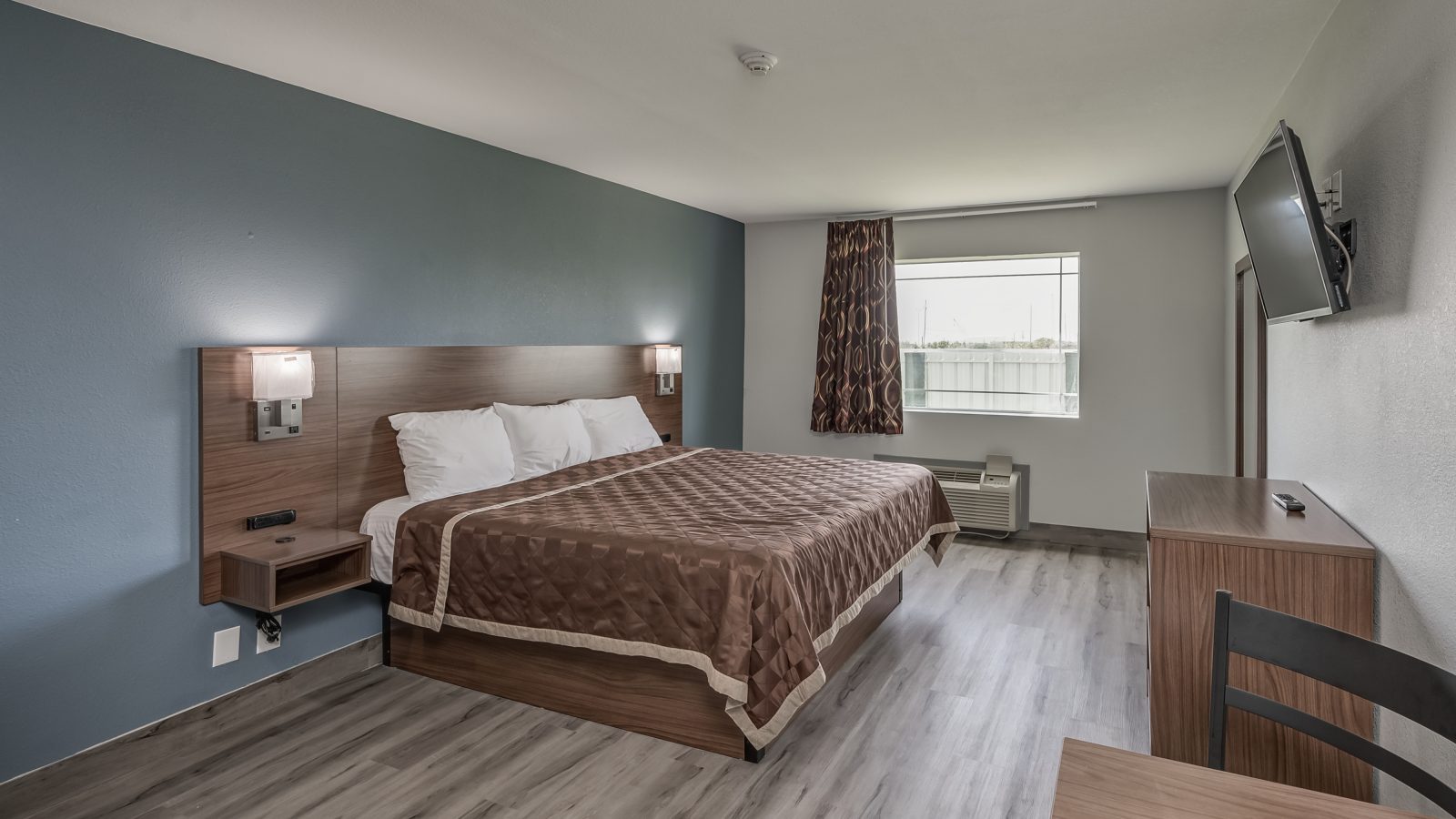 a hotel room with a bed, desk and television at The  Studios At Channelview