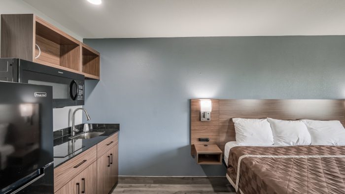 a hotel room with a bed, desk and sink at The  Studios At Channelview