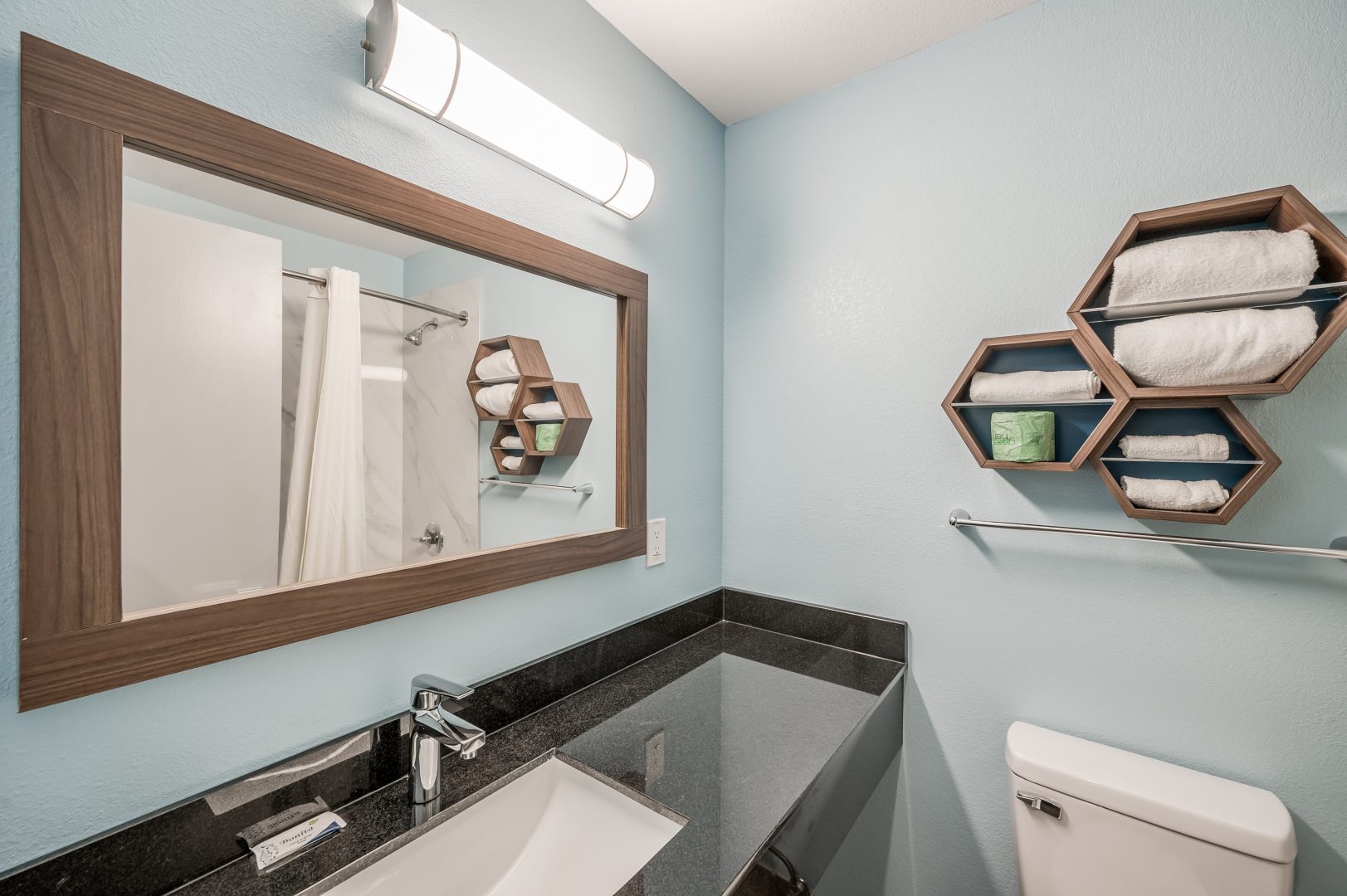 a bathroom with a sink, toilet and mirror at The  Studios At Channelview