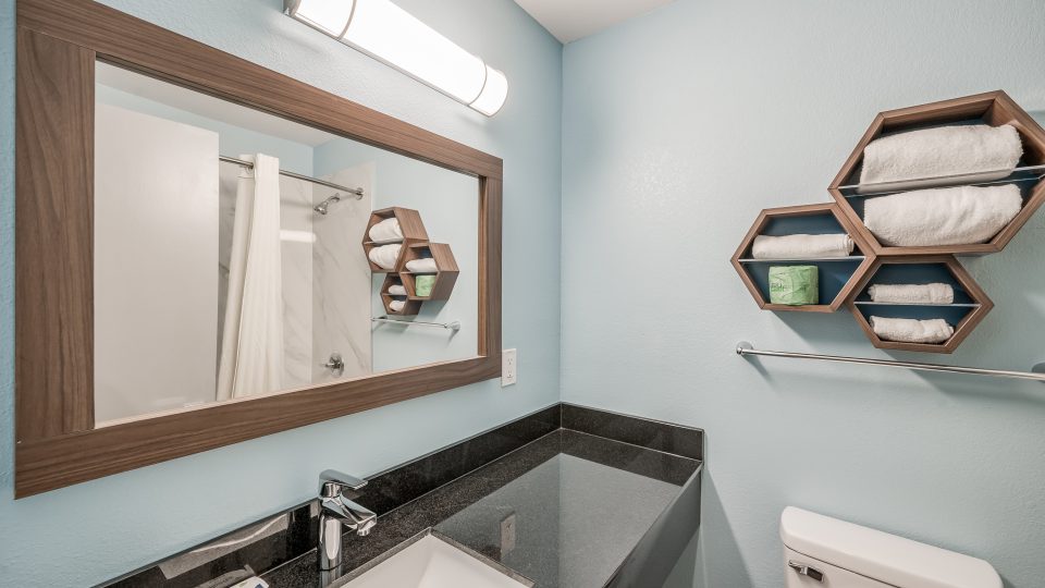 a bathroom with a sink, toilet and mirror at The  Studios At Channelview