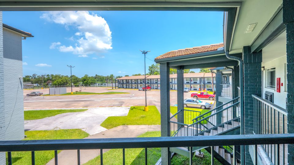 a balcony with a view of a parking lot and a building at The  Studios At Channelview